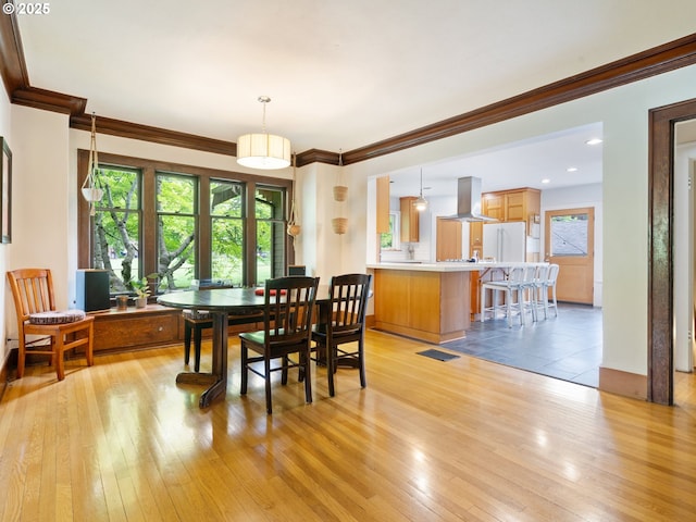 dining space featuring light wood-style flooring and ornamental molding