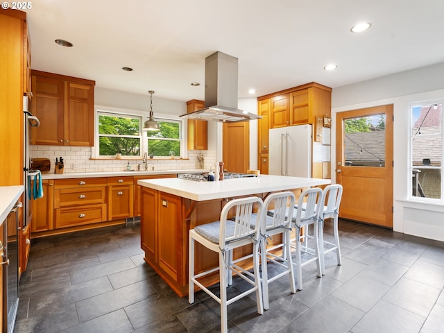 kitchen with freestanding refrigerator, island exhaust hood, a sink, decorative backsplash, and recessed lighting