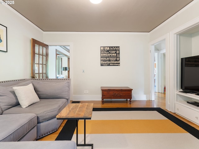 living room featuring wood finished floors, crown molding, and baseboards