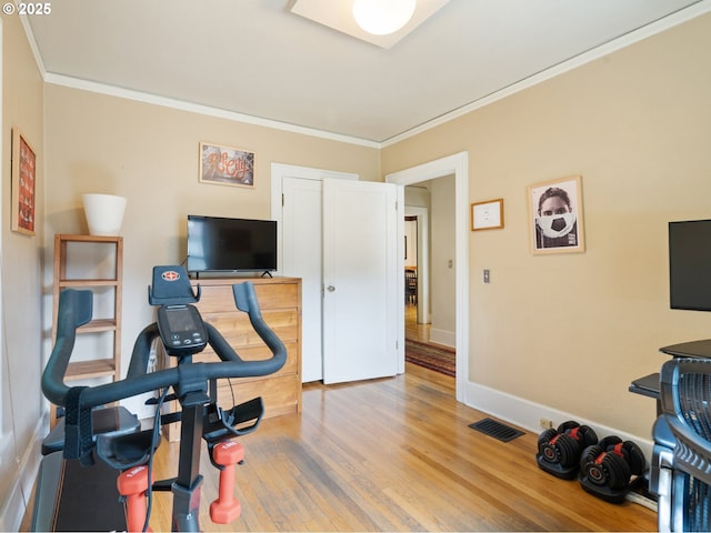 workout room featuring ornamental molding, wood finished floors, and baseboards