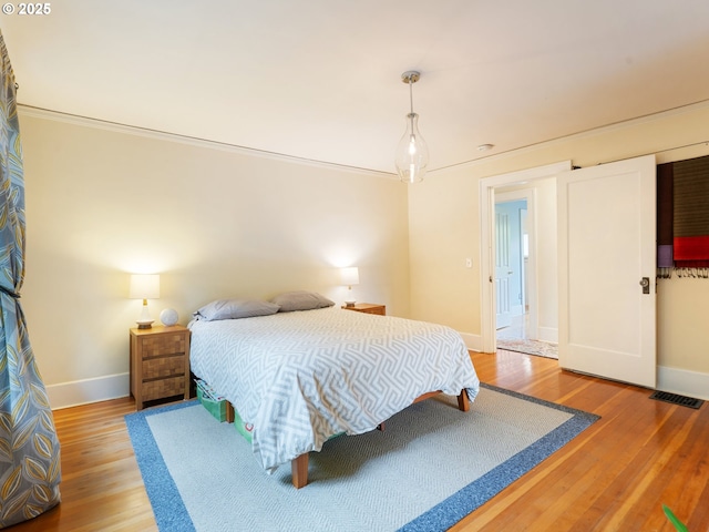 bedroom featuring baseboards, wood finished floors, and crown molding