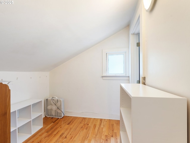 additional living space featuring vaulted ceiling and light wood-type flooring