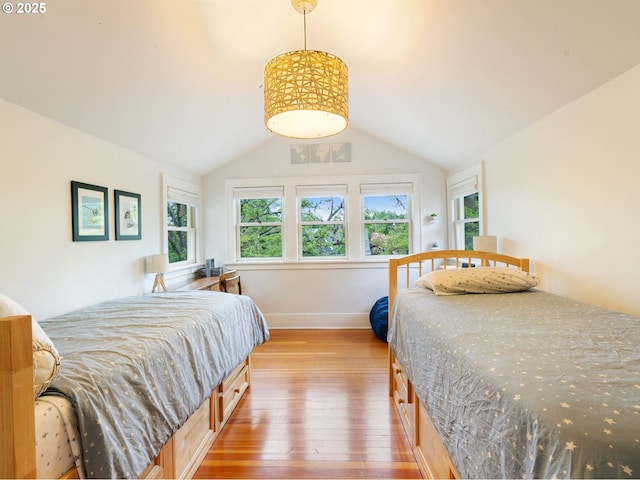 bedroom featuring wood-type flooring, vaulted ceiling, and baseboards