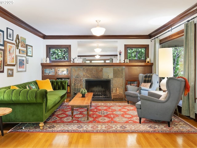 living room featuring plenty of natural light, wood finished floors, a fireplace, and ornamental molding