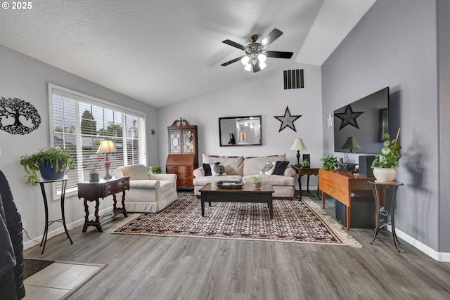 living area featuring vaulted ceiling, wood finished floors, baseboards, and a ceiling fan