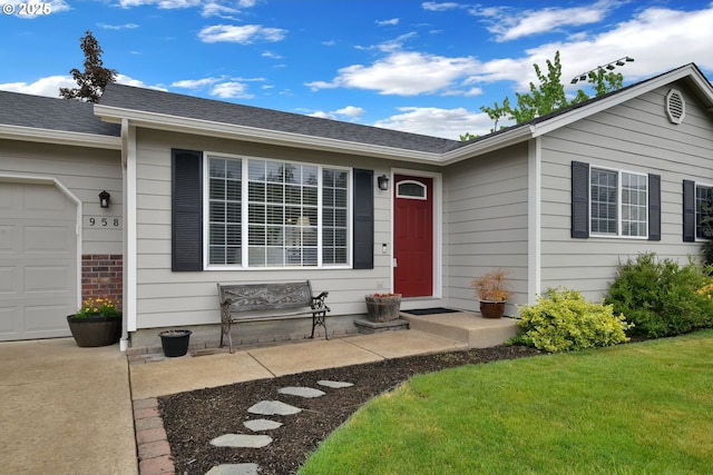 view of exterior entry with an attached garage, a lawn, and roof with shingles