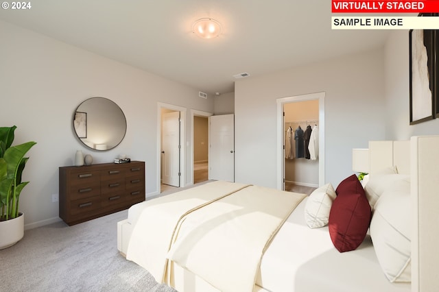 bedroom featuring light carpet, visible vents, and a walk in closet