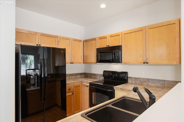 kitchen featuring light brown cabinets, tile counters, a sink, black appliances, and recessed lighting