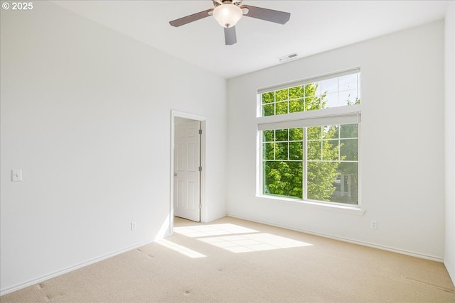 carpeted spare room with visible vents, baseboards, and ceiling fan