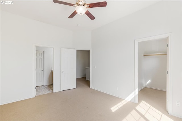 unfurnished bedroom featuring a spacious closet, baseboards, light carpet, and a closet