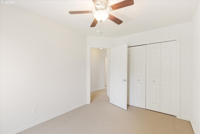 unfurnished bedroom featuring ceiling fan, baseboards, a closet, and light colored carpet