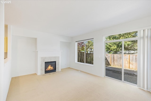 unfurnished living room with baseboards, light carpet, and a tiled fireplace