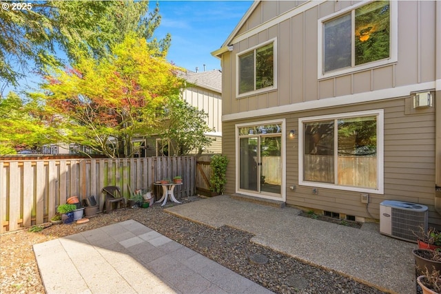 back of house with central air condition unit, a patio, board and batten siding, and a fenced backyard
