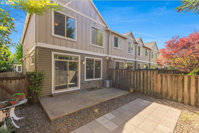 rear view of house featuring a residential view, a fenced backyard, central AC unit, board and batten siding, and a patio