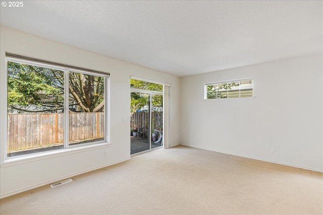 unfurnished room featuring baseboards, visible vents, and light colored carpet