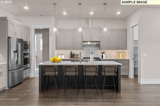 kitchen featuring sink, a breakfast bar area, gray cabinetry, stainless steel appliances, and an island with sink