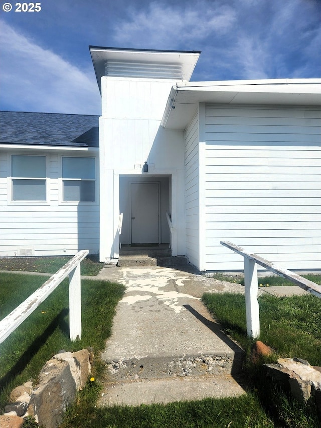 doorway to property featuring roof with shingles