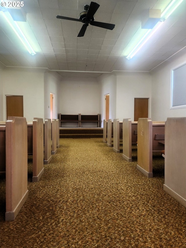 below grade area featuring baseboards, carpet, and ceiling fan