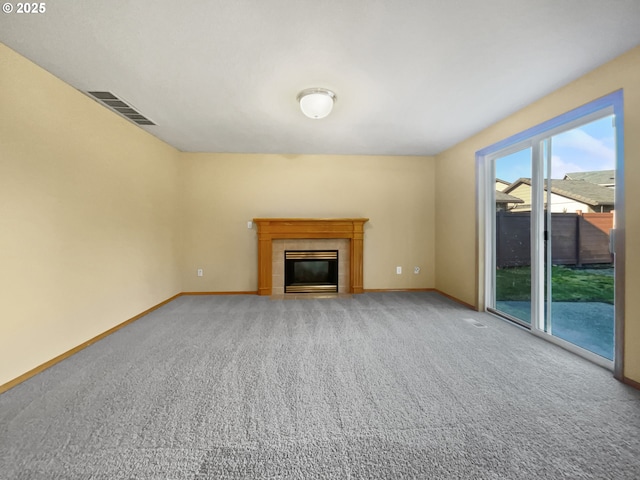 unfurnished living room featuring carpet, baseboards, visible vents, and a tiled fireplace