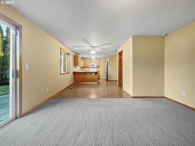 unfurnished living room with ceiling fan, carpet floors, and baseboards