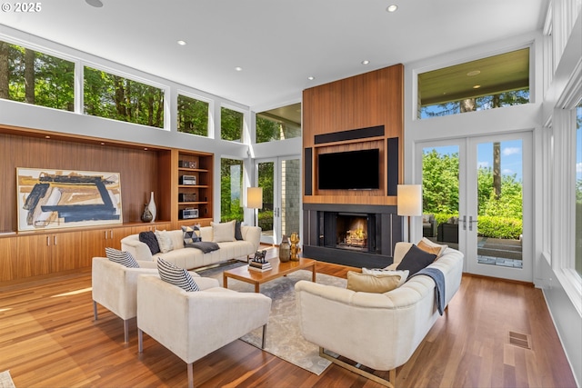 4140 NW Thunder Crest Rd, Portland, OR 97229 - living area with a high ceiling, wood finished floors, a large fireplace, recessed lighting, and french doors