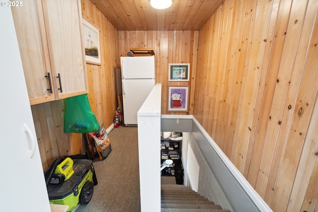 stairway with carpet floors, wooden ceiling, and wood walls