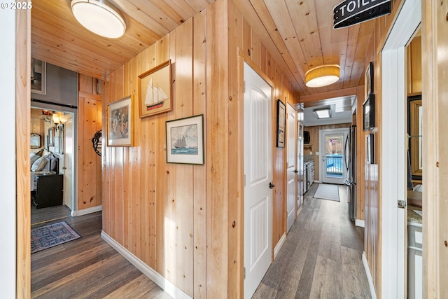 corridor featuring wooden walls, dark hardwood / wood-style flooring, and wooden ceiling