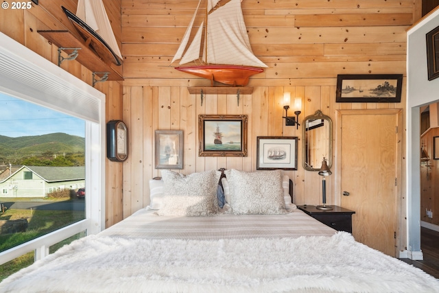 bedroom featuring a mountain view, access to exterior, and wooden walls