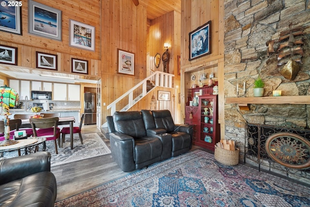 living room featuring a fireplace, wooden walls, hardwood / wood-style floors, and a high ceiling