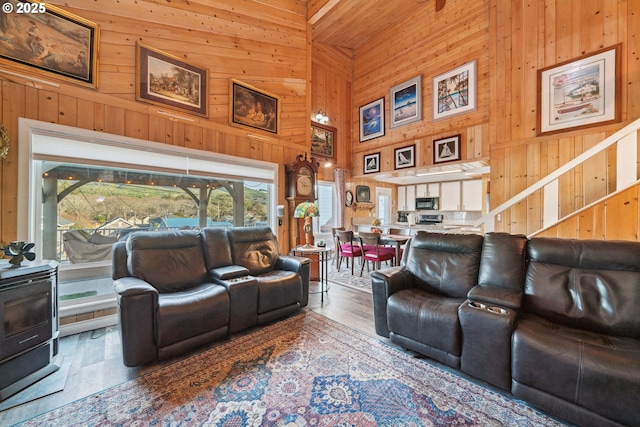 living room with hardwood / wood-style flooring, a towering ceiling, and wood walls