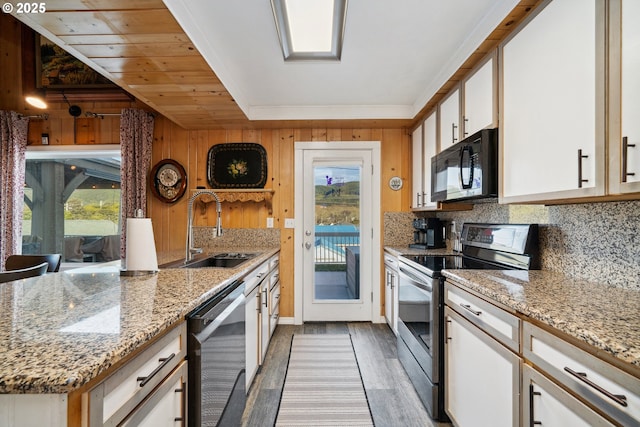 kitchen featuring stainless steel electric stove, sink, dishwashing machine, white cabinets, and light stone countertops