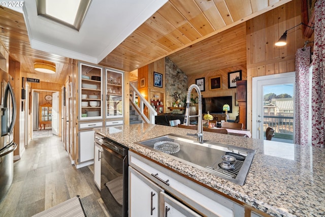 kitchen with white cabinetry, dishwasher, sink, and wooden walls