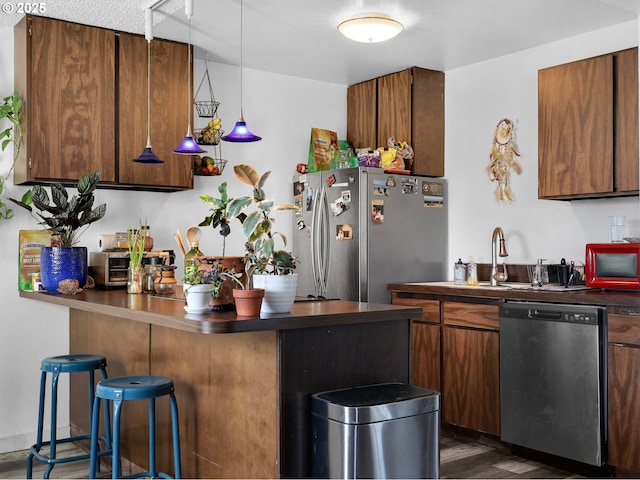 346 NE Skipanon Dr Unit 46, Warrenton, OR 97146 - kitchen with appliances with stainless steel finishes, dark countertops, dark wood-type flooring, a peninsula, and a kitchen breakfast bar