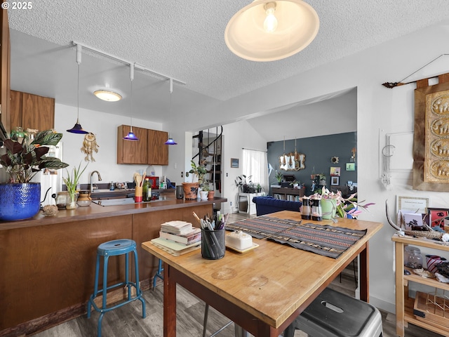 346 NE Skipanon Dr Unit 46, Warrenton, OR 97146 - kitchen featuring a textured ceiling, wood finished floors, brown cabinets, a peninsula, and a chandelier