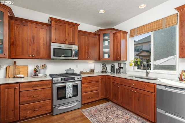 13765 SW Florentine Ave, Portland, OR 97223 - kitchen with appliances with stainless steel finishes, a sink, wood finished floors, light countertops, and glass insert cabinets