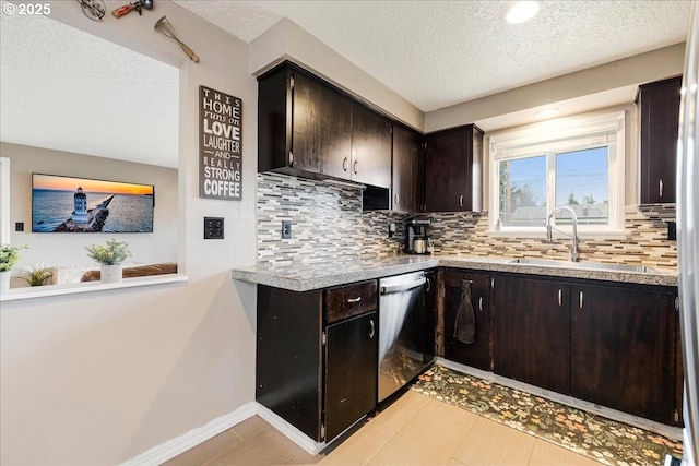 kitchen with a sink, backsplash, baseboards, light countertops, and stainless steel dishwasher