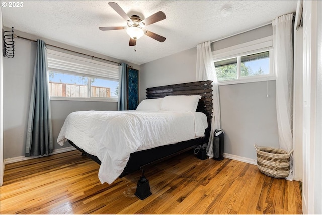 bedroom with baseboards, a textured ceiling, wood finished floors, and a ceiling fan