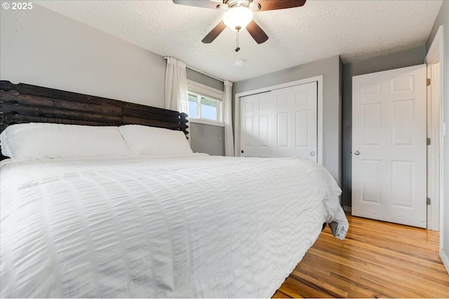 bedroom with a ceiling fan, light wood-style floors, a closet, and a textured ceiling