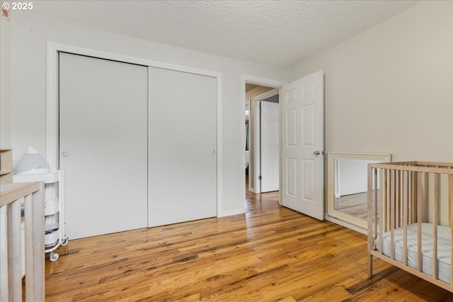 bedroom featuring a closet, light wood finished floors, and a textured ceiling