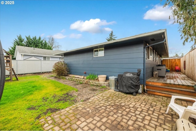 back of property with a patio area, a lawn, a wooden deck, and a fenced backyard