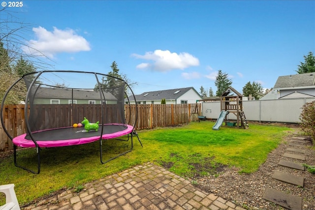 view of yard featuring a patio area, a playground, a trampoline, and a fenced backyard