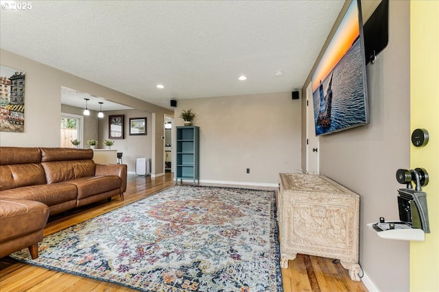 living room with recessed lighting, baseboards, a textured ceiling, and wood finished floors