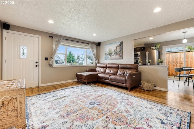 living room featuring recessed lighting, light wood-style floors, baseboards, and a textured ceiling