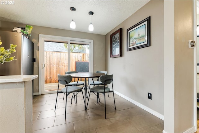 dining room featuring light tile patterned floors, baseboards, and a textured ceiling