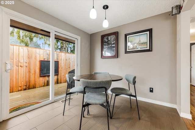 dining room featuring baseboards, a textured ceiling, and wood finished floors