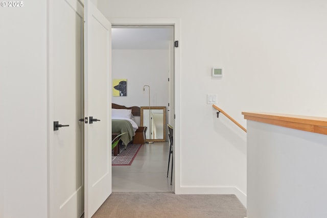 hall featuring an upstairs landing and carpet