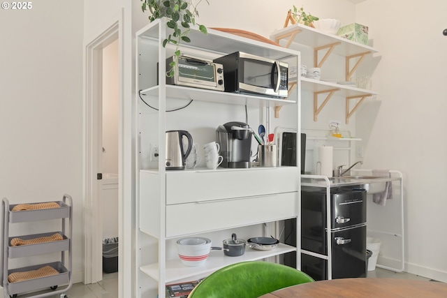 bar featuring baseboards, a sink, and stainless steel microwave