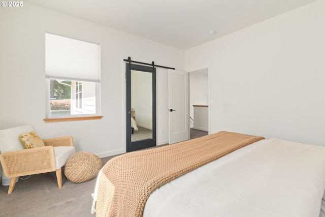 carpeted bedroom with baseboards and a barn door