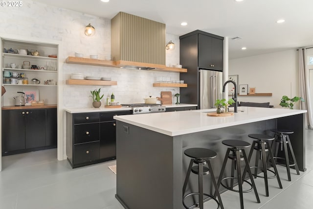 kitchen featuring a kitchen bar, open shelves, high end refrigerator, light countertops, and dark cabinetry