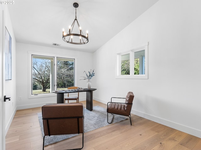 sitting room with light wood-type flooring, an inviting chandelier, and lofted ceiling